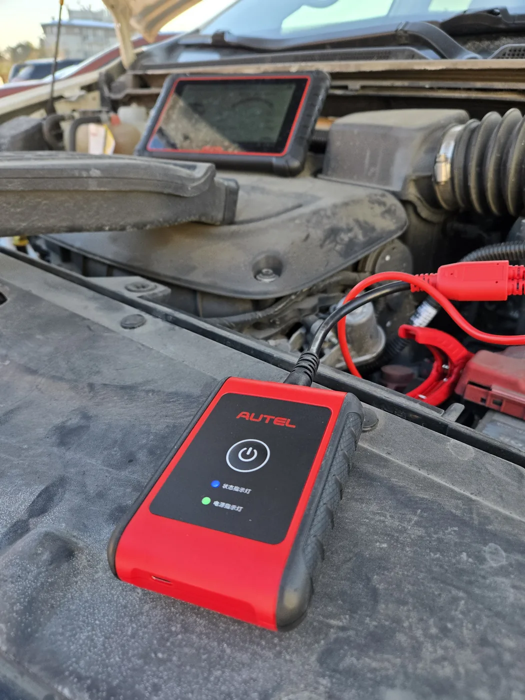 Moduł Autel BT506 podłączony do akumulatora podczas testu obciążeniowego, obok tablet diagnostyczny Autel