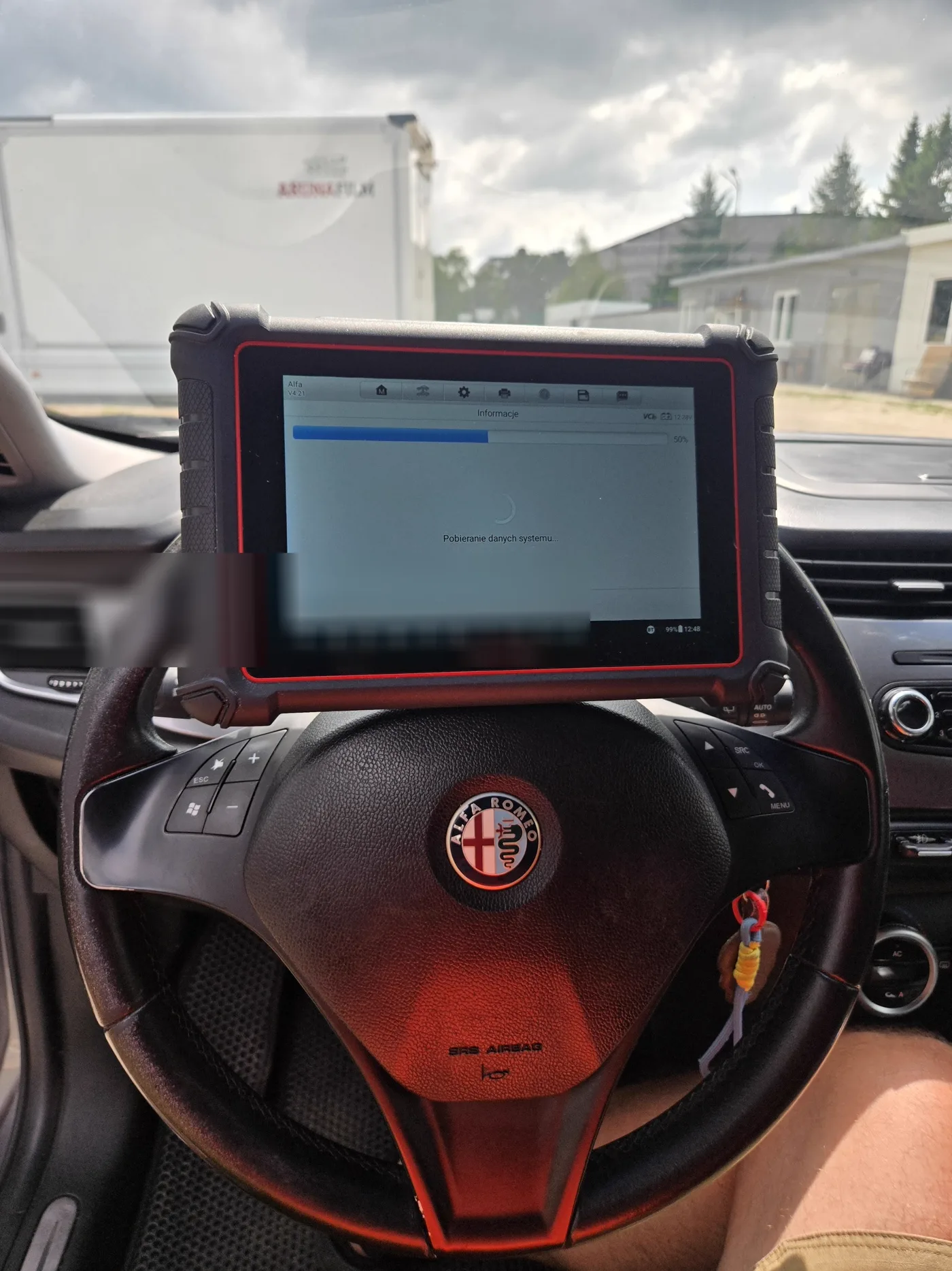 Tablet diagnostyczny oparty o kierownicę Alfy Romeo podczas pobierania danych systemowych pojazdu na początku autoskanu