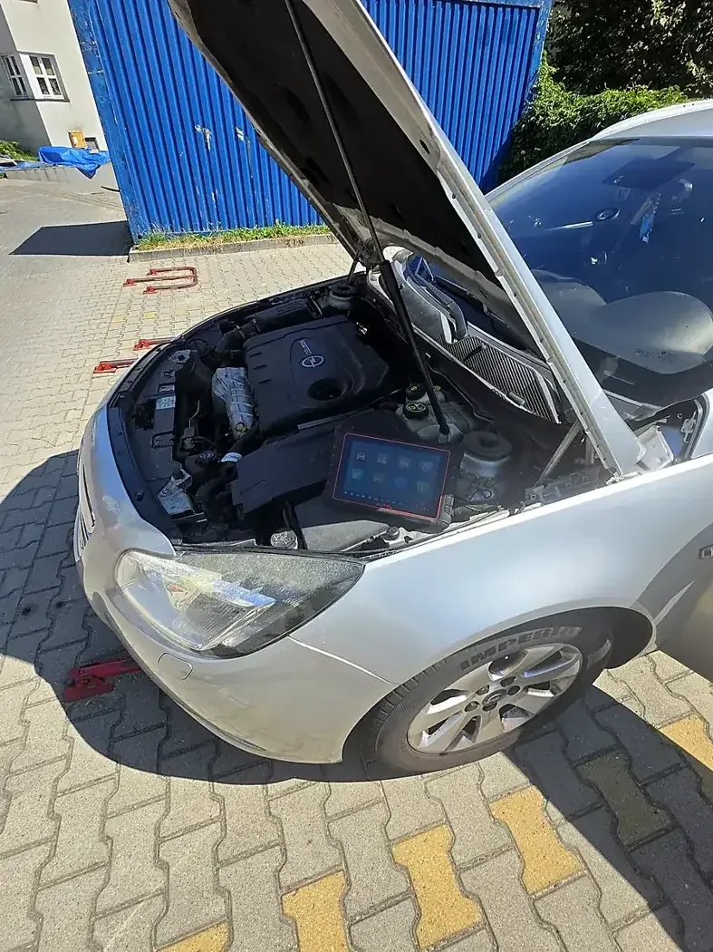 Tester Autel MK900-BT w komorze silnika srebrnego Opla Insignia z otwartą maską podczas diagnostyki komputerowej