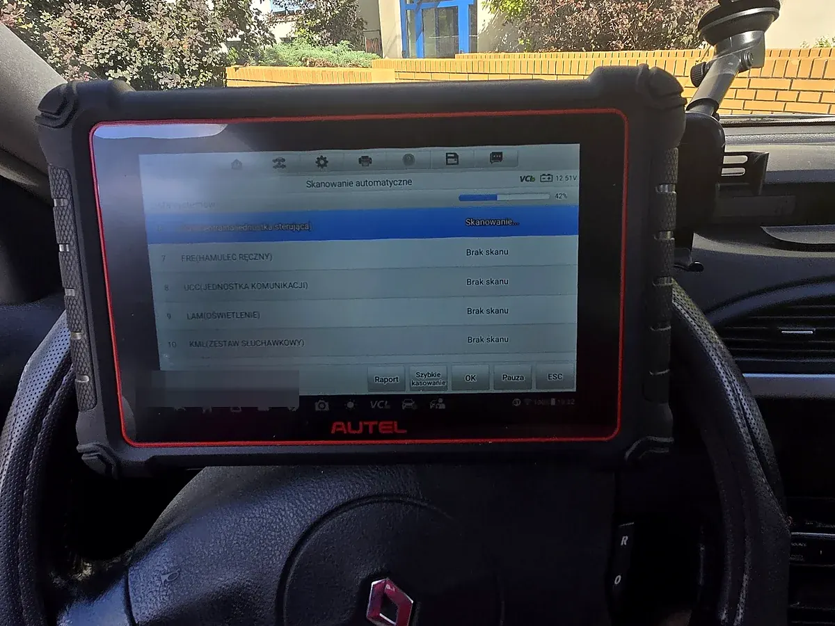 Tester Autel MaxiCOM MK900-BT oparty na kierownicy Renault Laguna II w trakcie skanowania automatycznego: pasek postępu 42 procent, napięcie 12,51 V, na liście modułów FRE hamulec ręczny, UCC, LAM oświetlenie i KML ze statusem Brak skanu