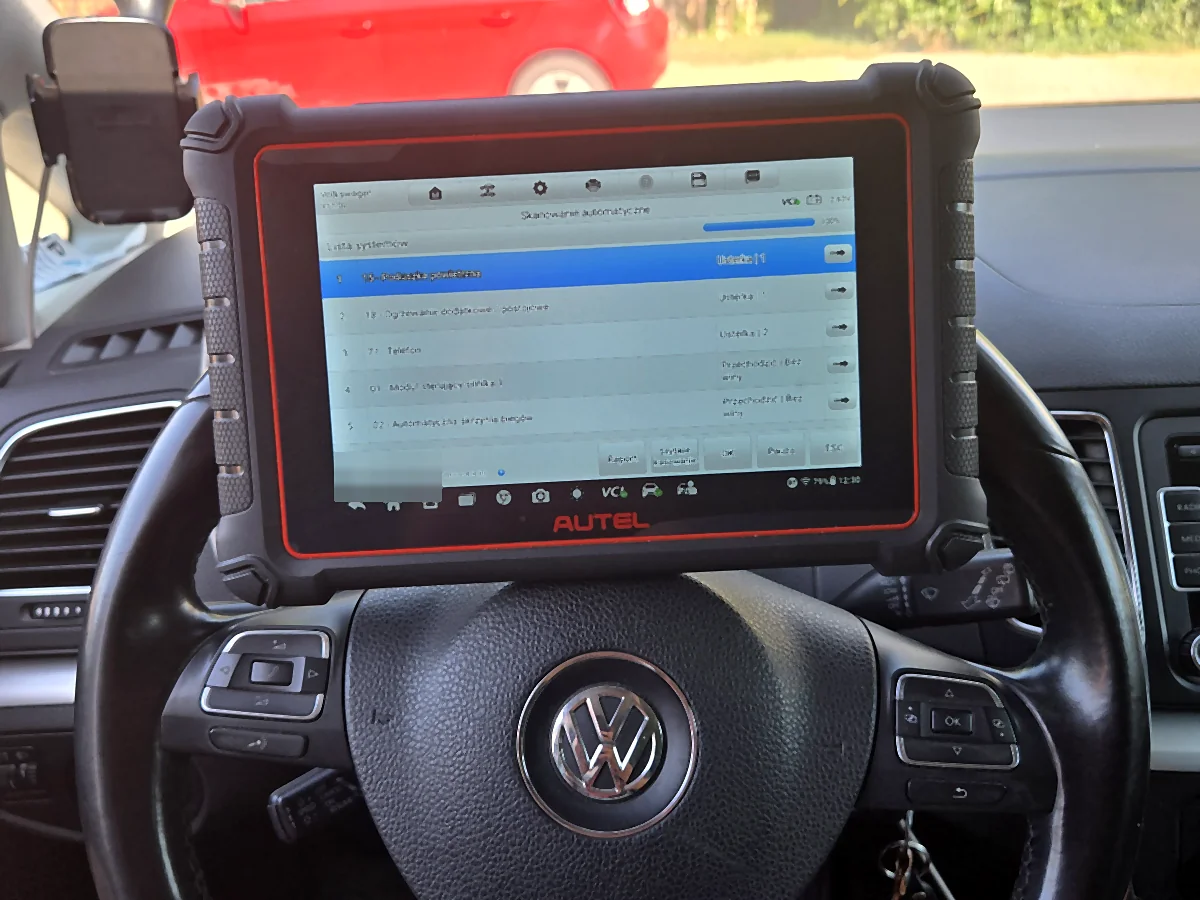 Ekran testera Autel MaxiCOM MK900-BT po skanowaniu automatycznym VW Sharana 7N: postęp 100 procent, napięcie 12,63 V, lista systemów z pozycjami 15 Poduszka powietrzna Usterka 1, 18 Ogrzewanie dodatkowe Usterka 1, 77 Telefon Usterka 2 oraz 01 Moduł sterujący silnika i 02 Automatyczna skrzynia biegów oznaczone Bez winy