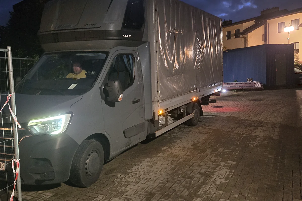 Renault Master III w wersji skrzyniowej z plandeką i nadbudową MAX zaparkowany nocą na kostce brukowej, włączone światła, pojazd dostawczy przygotowany do wymuszonego wypalania filtra DPF testerem Autel